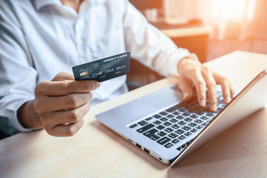 Young man use credit card for shopping payment online on laptop computer application or website. E-commerce and online shopping concept. uds
