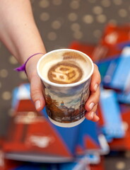A woman's hand carries coffee in a paper cup close-up