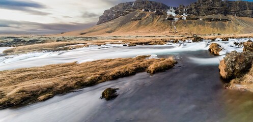 Panoramic view of the cliff and flowing rushing water on the river in Kirkjubæjarklaustur or Kirkjubaejarklaustur, Iceland. Nature, travel, winter background, or wallpaper