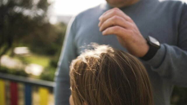 A tender moment between a father and child, showing affection and care in an outdoor park environment