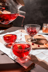 drops of red tea, woman pouring tea into a glass cup, hibiscus, tea with red berries, vitamin drink, winter tea for colds, lemon, red currant, black currant, raspberry, honey, cinnamon, anise