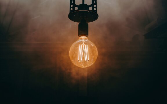 illuminated light bulb, Glowing vintage light bulb in smoky dark room.