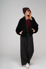 Trendy woman in stylish spring, autumn outfit looking away and smiling while posing on studio background.