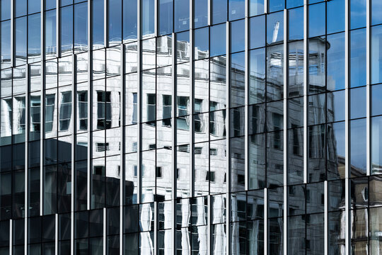 This image captures the fascinating reflections of a classic building on a modern glass facade, creating a dialogue between history and contemporary architecture.