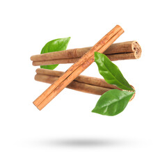 Cinnamon sticks and green leaves in air on white background