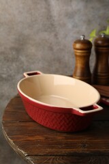 Ceramic casserole and shakers on wooden table, closeup