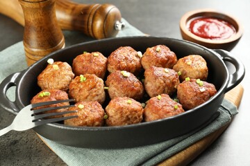 Tasty meatballs in baking dish served on grey table, closeup