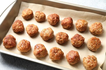 Many delicious meatballs in baking dish on grey textured table, closeup
