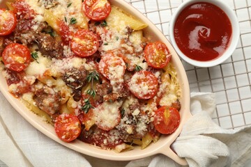 Delicious pasta casserole with cheese, tomatoes, minced meat and ketchup on white table, flat lay