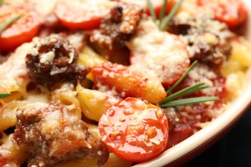 Delicious pasta casserole with cheese, tomatoes, minced meat and rosemary in baking dish, closeup
