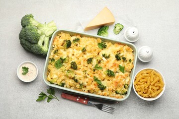 Tasty pasta casserole with cheese and broccoli served on grey table, flat lay