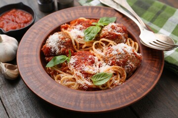Delicious pasta with meatballs, cheese and basil on wooden table, closeup