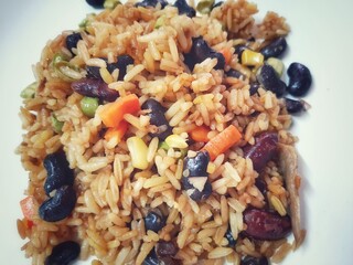 A delicious plate of fried rice with black beans, carrots, corn, and peas, offering a colorful and healthy plant-based meal full of flavor.