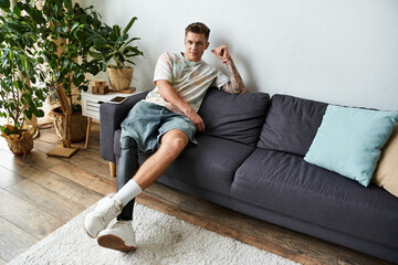 Handsome young man with a prosthetic leg lounging comfortably in a modern living room