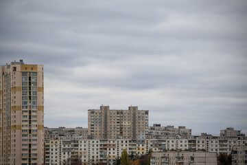 Fototapeta premium Urban landscape with gray high-rise buildings against a cloudy overcast sky.