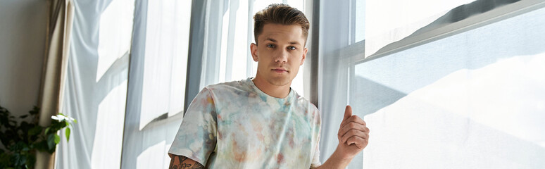 Young man with a prosthetic leg confidently posing in a modern, sunlit space