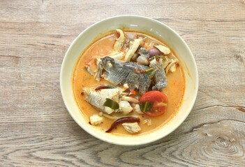 boiled bass fish head and mushroom in tom yum soup on plate
