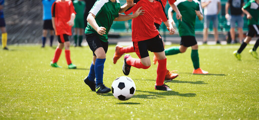 Football soccer match for children. Boys in red and green shirts playing football game on school tournament. Dynamic, action picture of kids competition during playing football. Sport background image