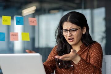 Upset and disappointed woman working in the middle of the office with a laptop close up....