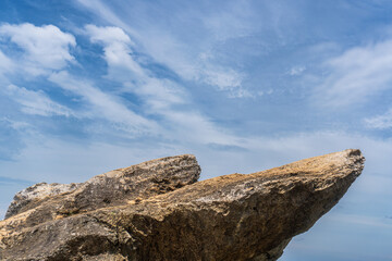 Two jagged rock protrusions stand prominently against a blue sky filled with feathery white clouds.