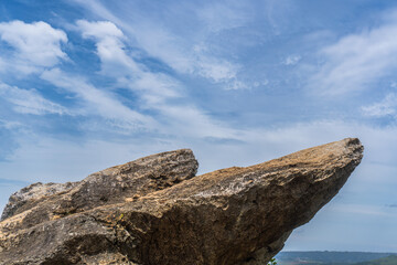 Two rock formations jut out against a bright blue sky with wispy white clouds.