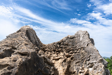 Dramatic rocky outcrop with layered texture under a blue sky with wispy white clouds