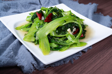 Stir-fried vegetable lettuce tips on a white plate