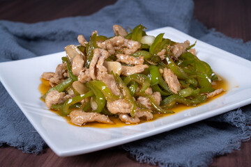 Shredded pork with green pepper on a white plate on the table