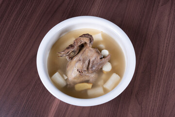 Iron stick yam pigeon soup in a white ceramic soup bowl