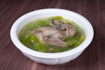 Pigeon tonic soup with lettuce in a white soup bowl
