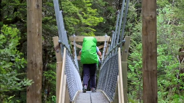 The hikers walking on a suspension bridge in the Routeburn Track in the South Island of New Zealand