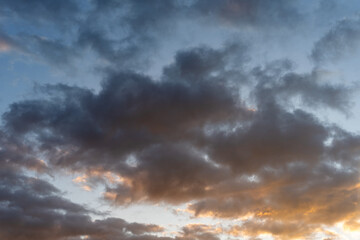 Obraz premium Dramatic dark and yellow-orange clouds under a blue sky.