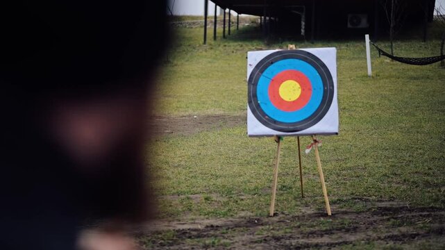 Close-up of archery in action, focusing on the bow being aimed at a target several meters away.