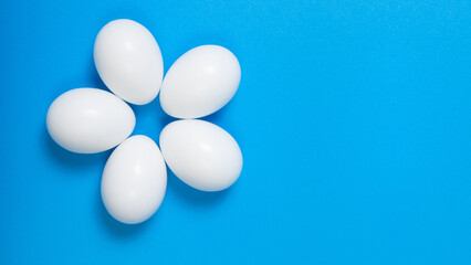 White color Eggs. Happy Easter poster, spring Christian greeting card, template sale banner, healthy menu. Bright blue color background, flat lay, copy space