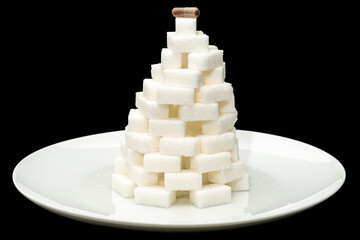 Sugar pyramid made of lump sugar on a white plate. On top of the pyramid a pill (capsule). Conceptual.