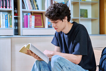 Portrait of college student guy reading bool inside classroom of educational building