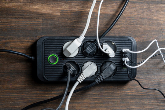 AC outlet multiprise power strip with USB plugs at home. Electrical plug in outlet socket at home. Energy efficiency concept. Black plastic power strip with extension cord. Multi-outlet strip