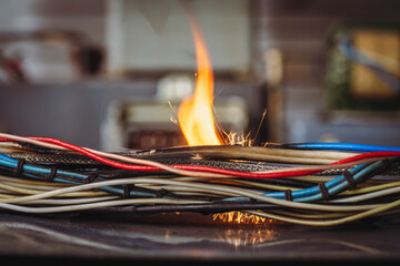 Flames, sparks, smoke between electrical cables, closeup. Short circuit in the twisted wires from...