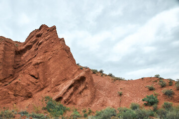 Fototapeta premium Konorchek canyon, sheer cliffs subject to erosion. Travel destination, famous landmark Kyrgyzstan, Central Asia. Rock formation, natural landscape, hiking trekking area, sandstone red rocks