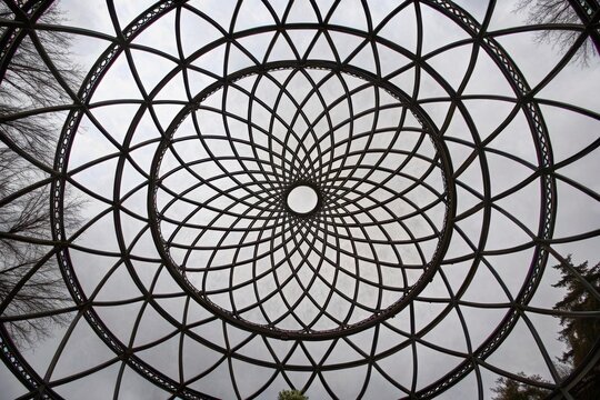 Intricate Metal Lattice Dome Structure Viewed from Below, Showing Sky Through Geometric Pattern