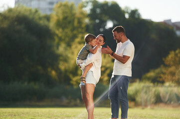 Fototapeta premium Family bonding. Mother and father are with son outdoors on the field