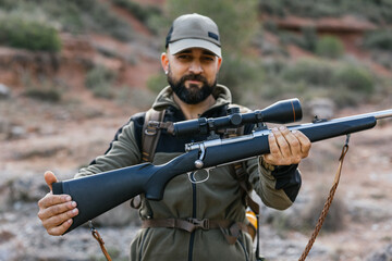 Fototapeta premium Hunter showing modern hunting rifle with scope in nature