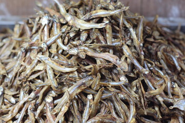 Crispy small fish placed on the stall for sale. Close up of stacked dried anchovies. A pile of dried anchovies displayed in a fish market, Little dried fish in an Asian fish market.
