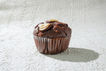 A chocolate almond topped with almonds, set against a textured white background for a clean and appealing look