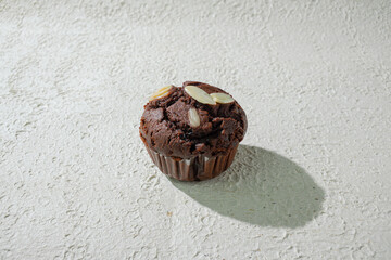 A chocolate almond topped with almonds, set against a textured white background for a clean and appealing look