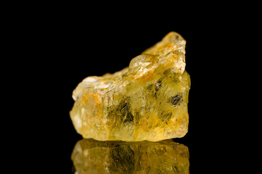 Closeup natural rough golden beryl (beryl group) gemstone on dark background (selective focus)