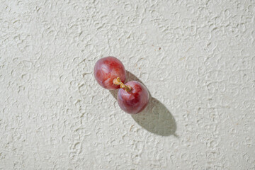 Close up of vibrant red grapes against a textured white background, highlighting their freshness and texture