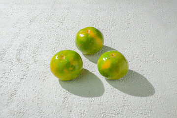 Green orange gradient citrus fruit isolated on a textured white background, showcasing its vibrant color transition