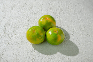 Green orange gradient citrus fruit isolated on a textured white background, showcasing its vibrant color transition