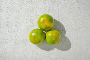 Green orange gradient citrus fruit isolated on a textured white background, showcasing its vibrant color transition
